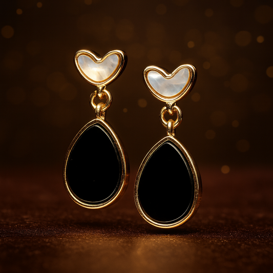 Pair of heart-shaped earrings with black teardrop designs on a dark background
