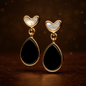 Pair of heart-shaped earrings with black teardrop designs on a dark background
