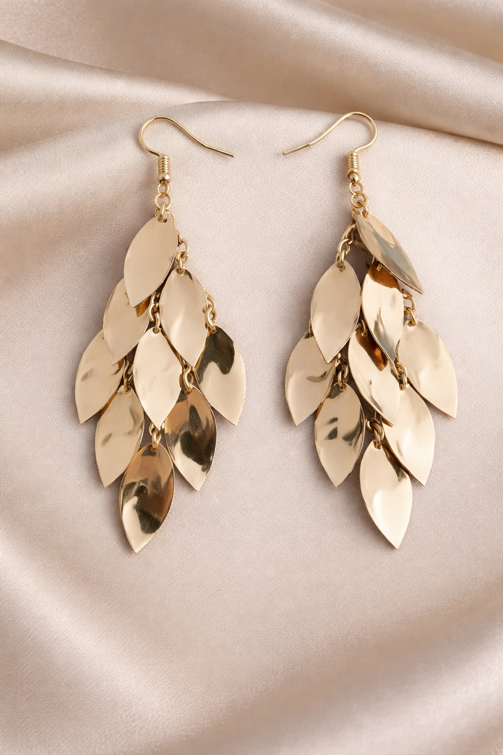 Gold leaf-shaped earrings on a rose cloth