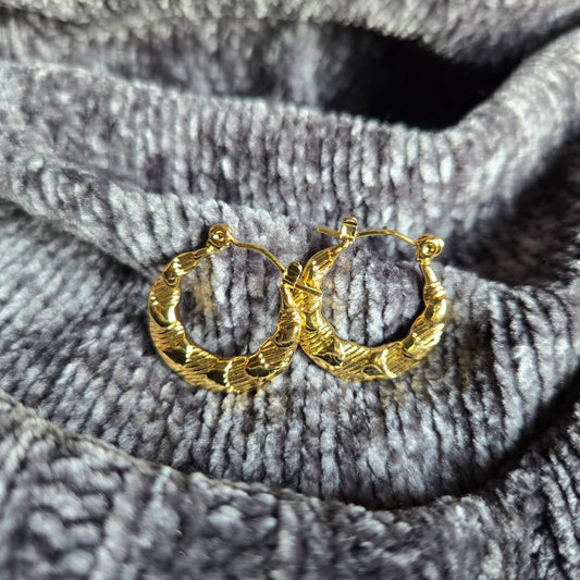 Gold hoop earrings on a textured gray fabric background