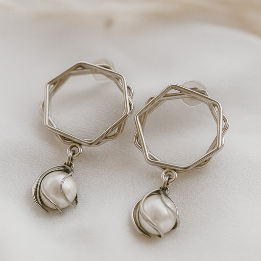 Silver geometric earrings with pearl-like droplets on a soft white background