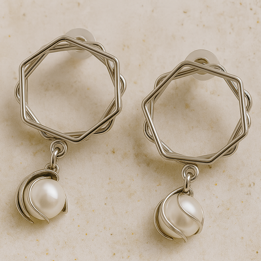 Pair of silver earrings with hexagonal designs and pearl drops on a beige background