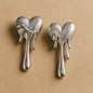 Pair of silver heart-shaped earrings on a beige background