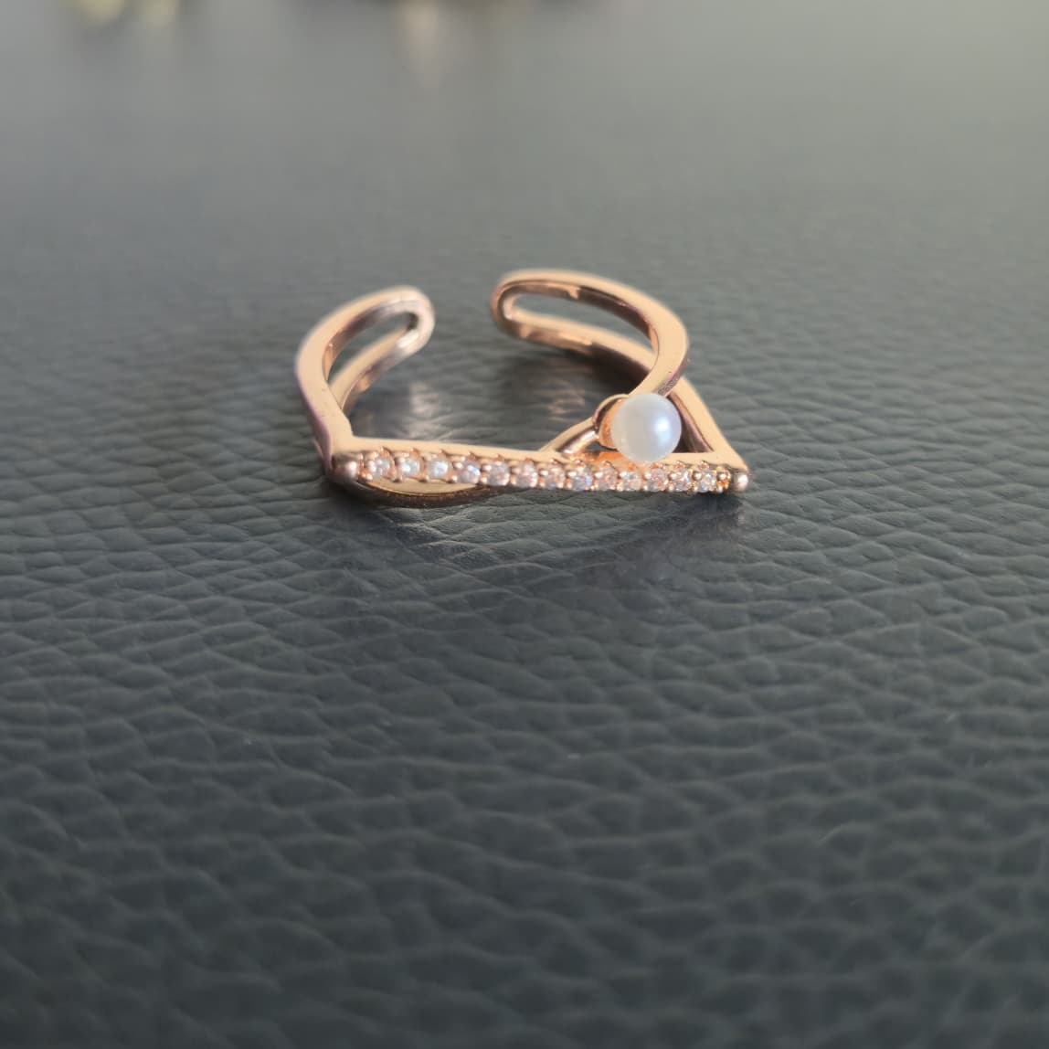 Rose gold ring with a central gemstone on a dark textured surface