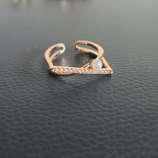 Rose gold ring with a central gemstone on a dark textured surface
