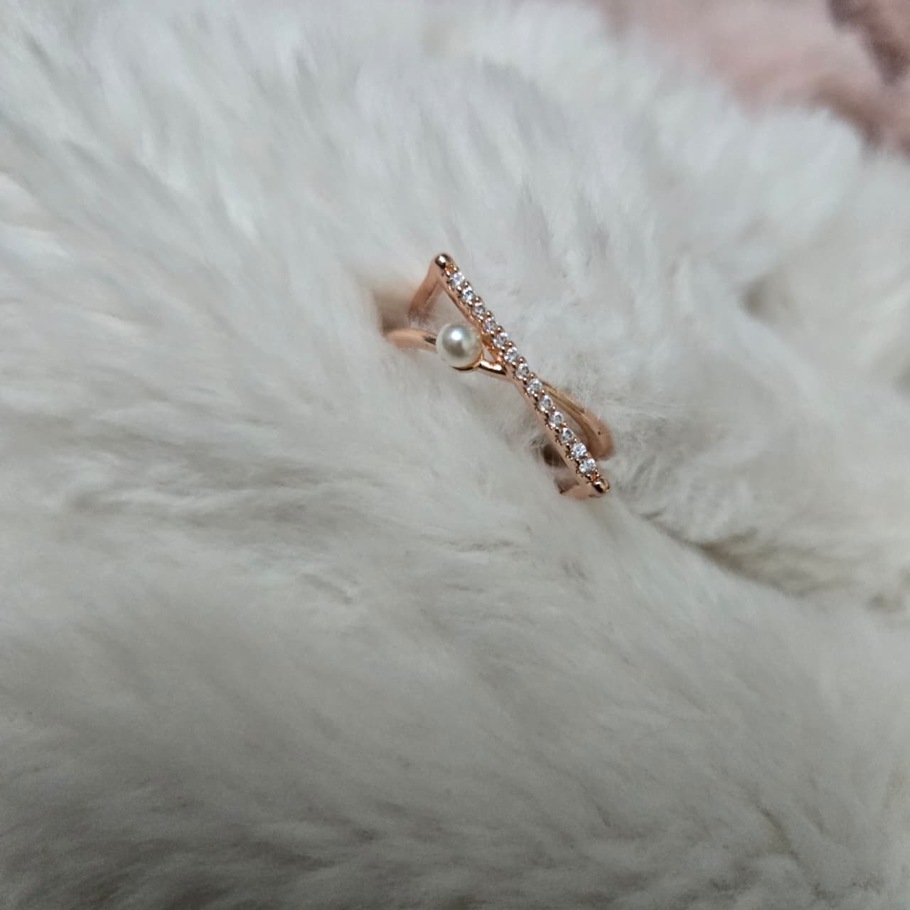 Rose gold ring with a pearl and small diamonds on a fluffy white surface