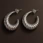Pair of silver hoop earrings on a dark brown background