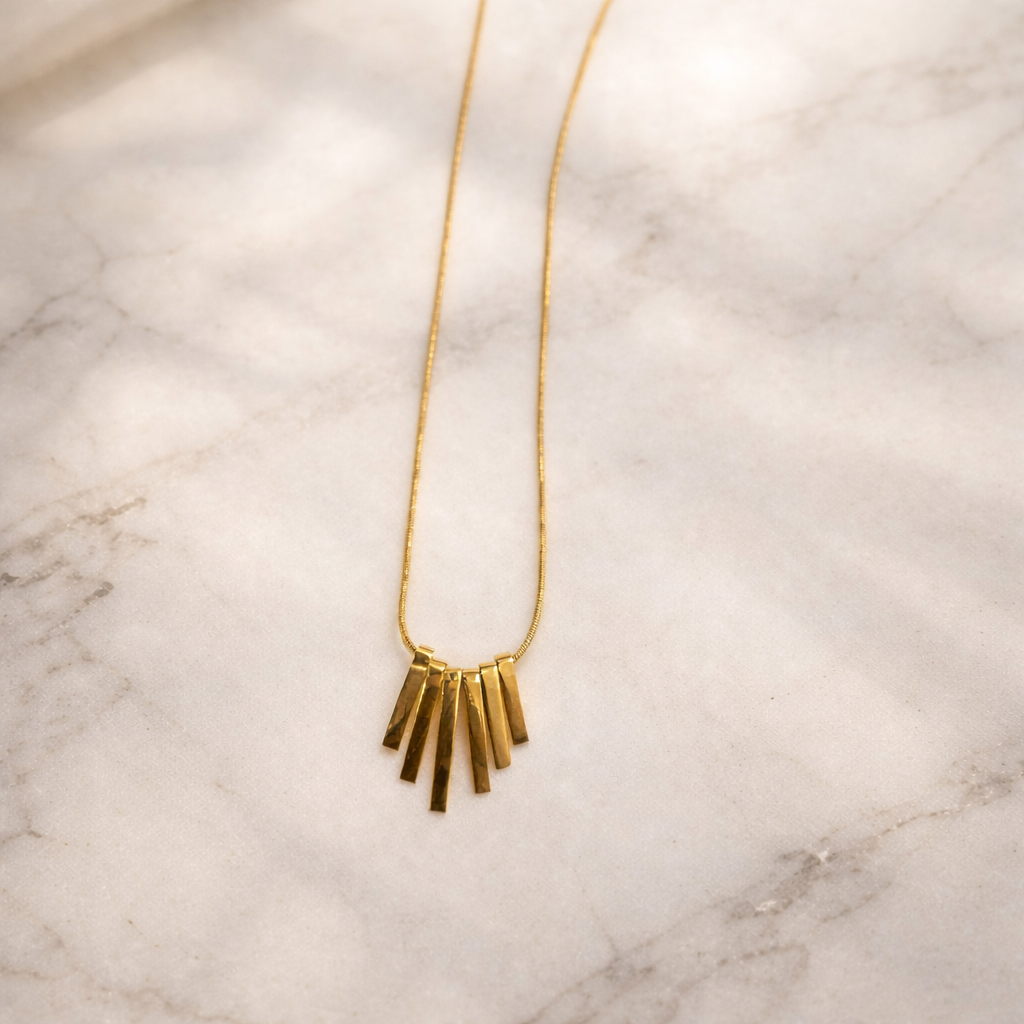 the golden pendant on a white marble background.