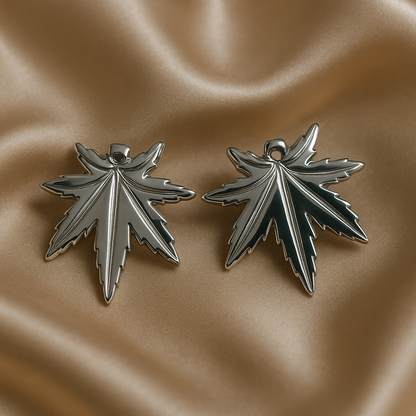 Silver leaf-shaped earrings on a beige fabric background