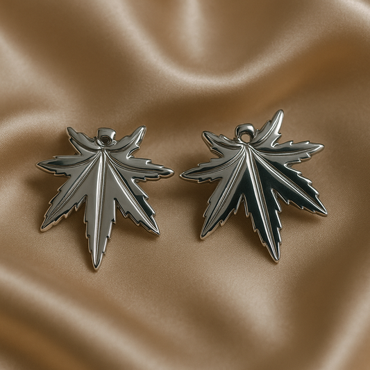 Silver leaf-shaped earrings on a beige fabric background