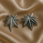 Silver leaf-shaped earrings on a beige fabric background