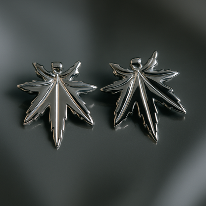 Two silver leaf-shaped pendants on a dark gray background