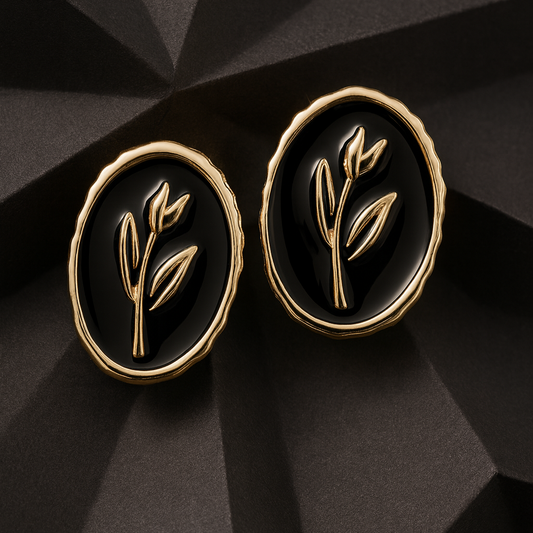 Elegant oval black and gold stud earrings with a raised botanical design on a glossy enamel finish