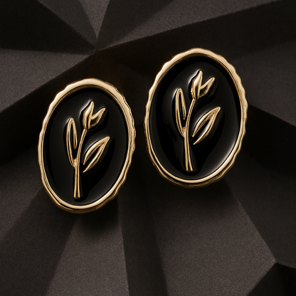 Elegant oval black and gold stud earrings with a raised botanical design on a glossy enamel finish