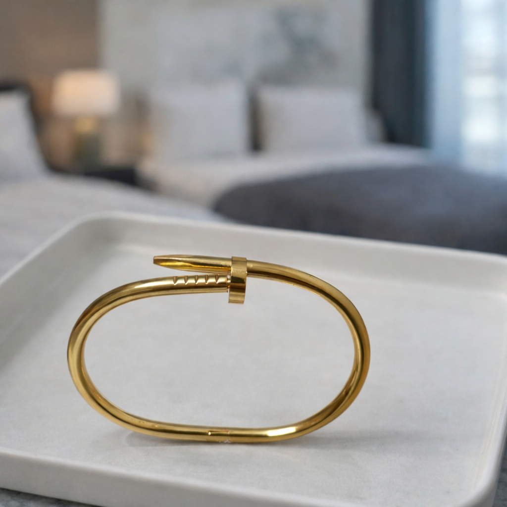 A timeless nail-shaped bracelet with gold tone and unique wrapped design on a white plate. 