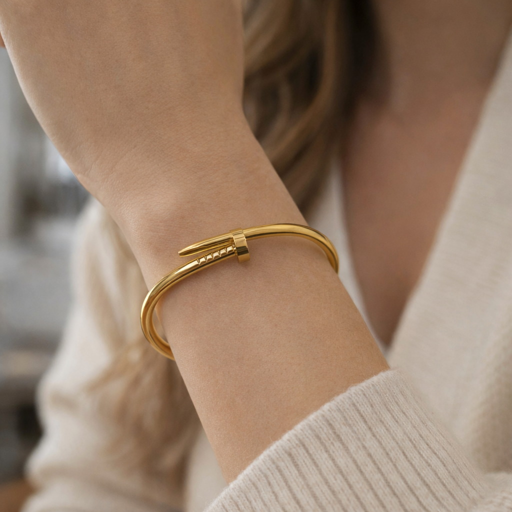 A woman wearing a timeless nail-shaped bracelet with gold tone and unique wrapped design.
