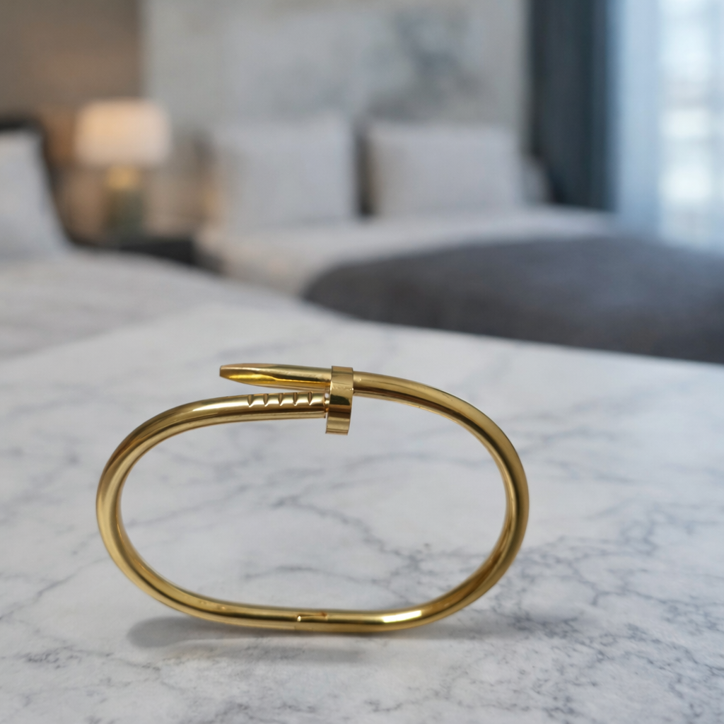 A timeless nail-shaped bracelet with gold tone and unique wrapped design on a white background.  