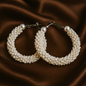 Pearl hoop earrings on a brown fabric background