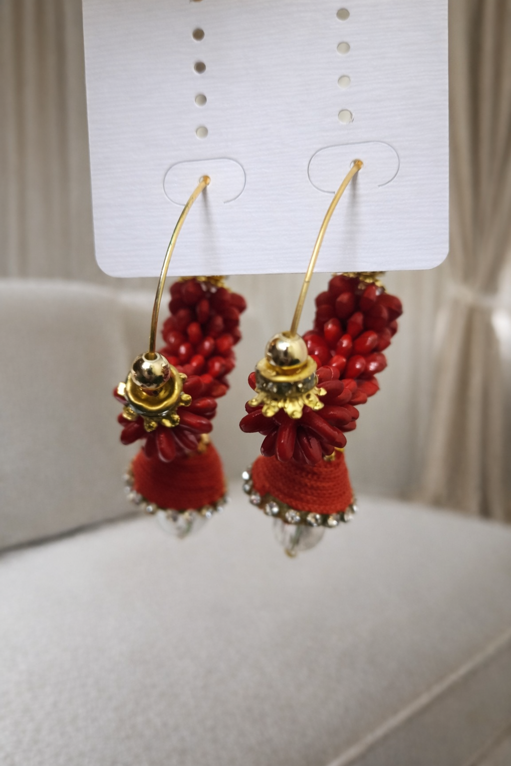 The earrings dangling from a white cardboard on a couch background 