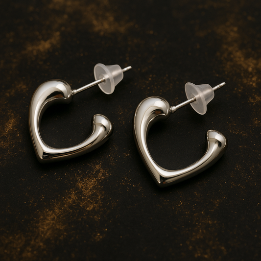 Pair of silver-toned open-heart stud earrings with a polished finish and transparent backings, displayed on a dark textured background.