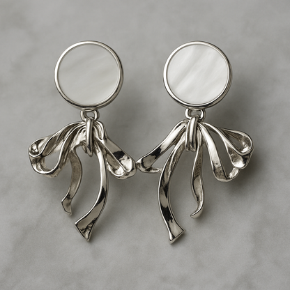 Elegant silver earrings with round mother-of-pearl studs and flowing ribbon-like drop design.