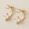 Gold hoop earrings with clear gemstones on a beige background