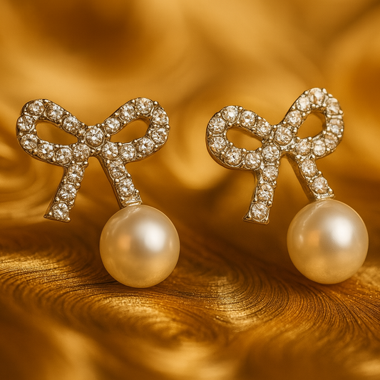 A pair of elegant stud earrings featuring crystal-studded bow designs with dangling white pearls.