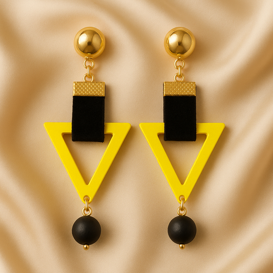Sunny Edge Drops earrings featuring bright yellow triangular frames, black velvet straps, gold-tone studs, and black bead dangles, displayed on a satin background