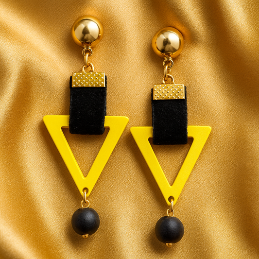 Sunny Edge Drops earrings featuring bright yellow triangular frames, black velvet straps, gold-tone studs, and black bead dangles, displayed on a satin background