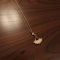 Gold necklace with a leaf pendant on a wooden surface