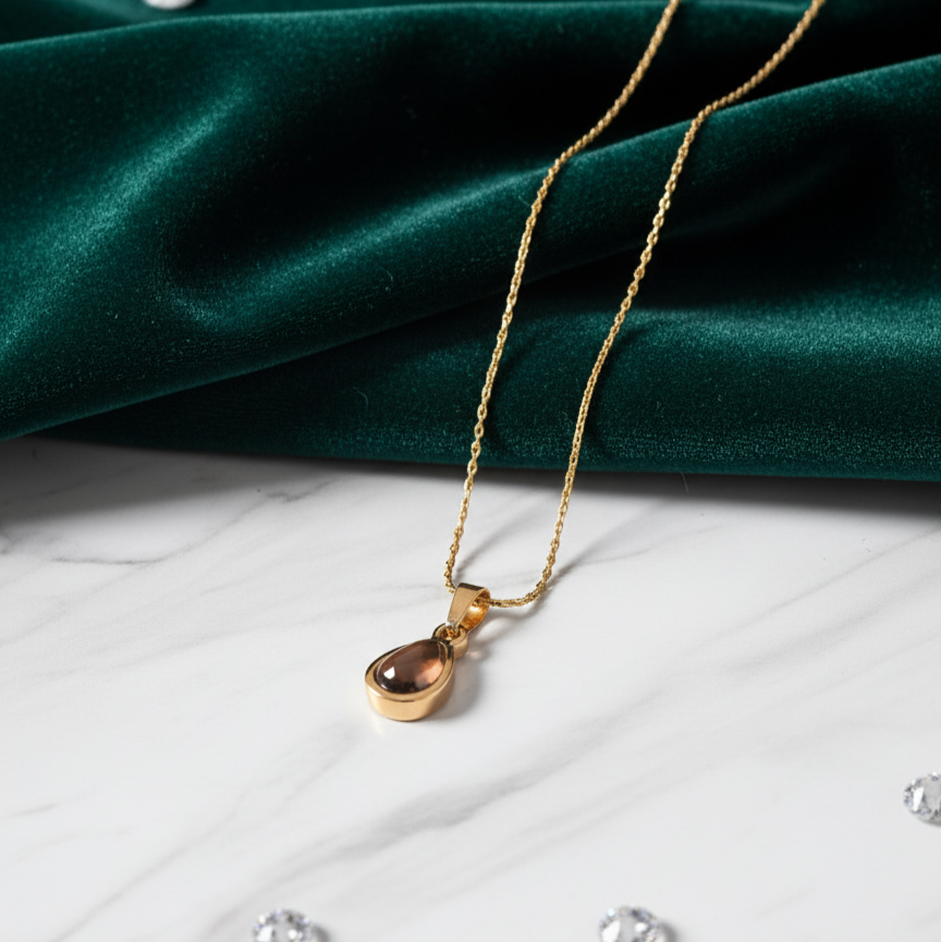 Gold necklace with a pendant on a green fabric background