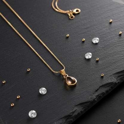 Gold necklace with a teardrop pendant on a dark surface