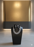 Jewelry set on a black stand against a warm-toned wall.