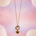 Gold necklace with a heart pendant on a pastel background