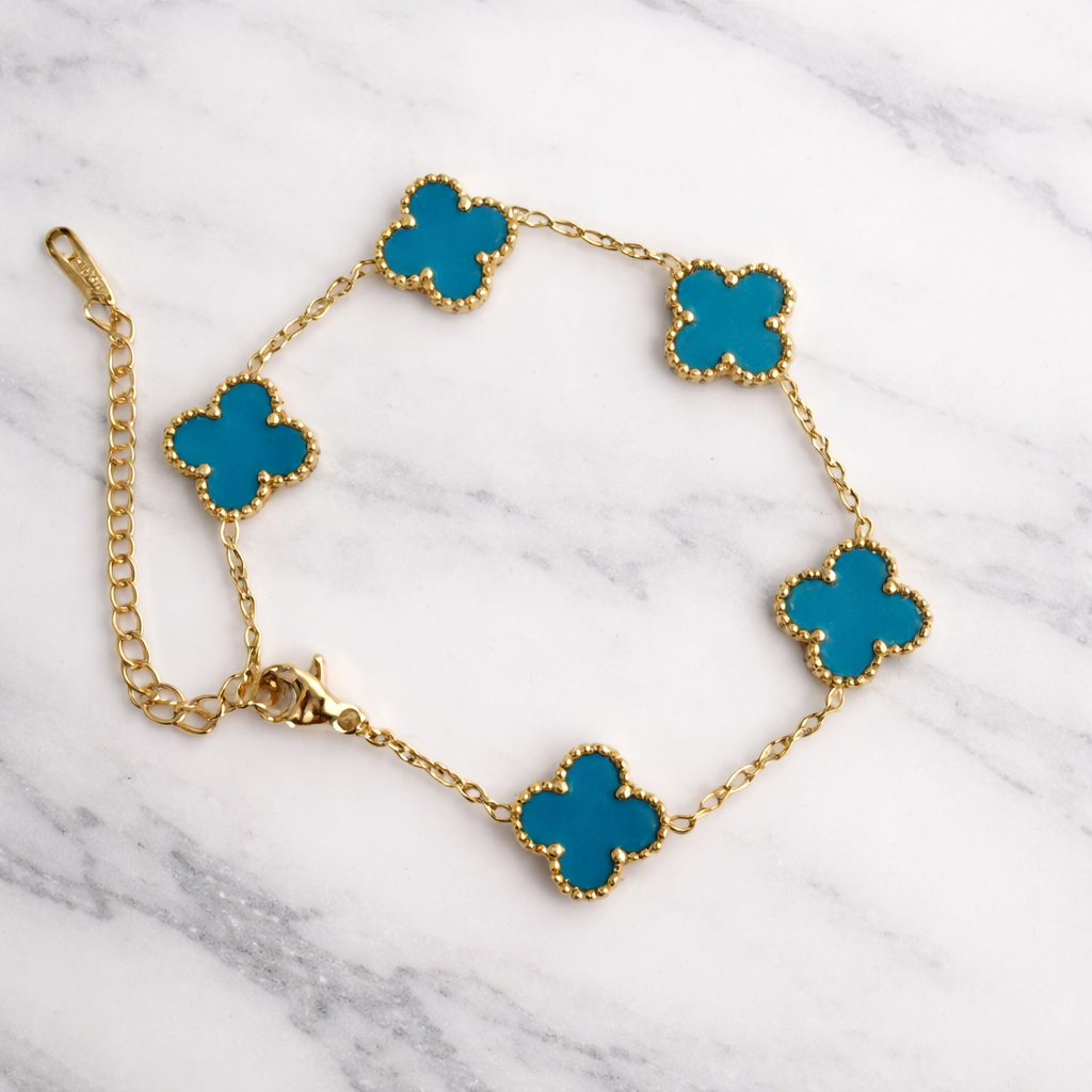 gold-tone clover charm bracelet, featuring turquoise clover stations framed in a delicate beaded border on a white background. 