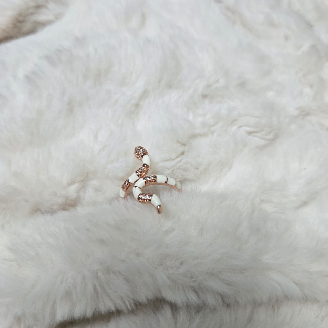 Rose gold and white beaded earring on a white fur background