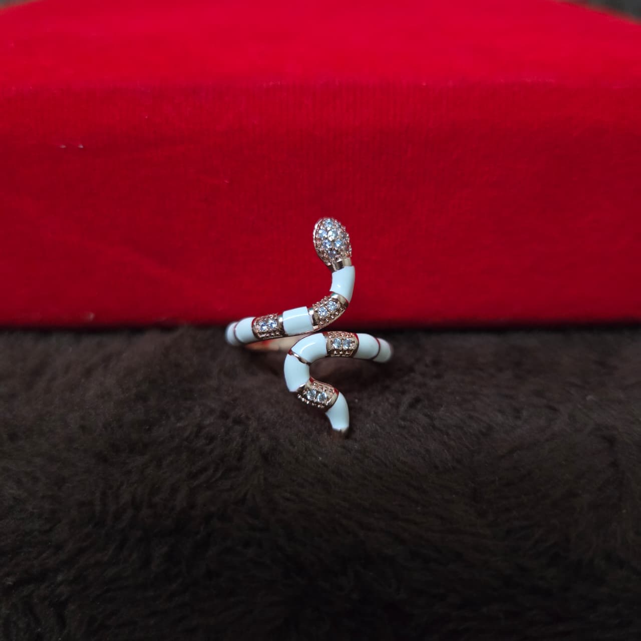 Serpentine ring with white and rose gold design on a red and brown textured background