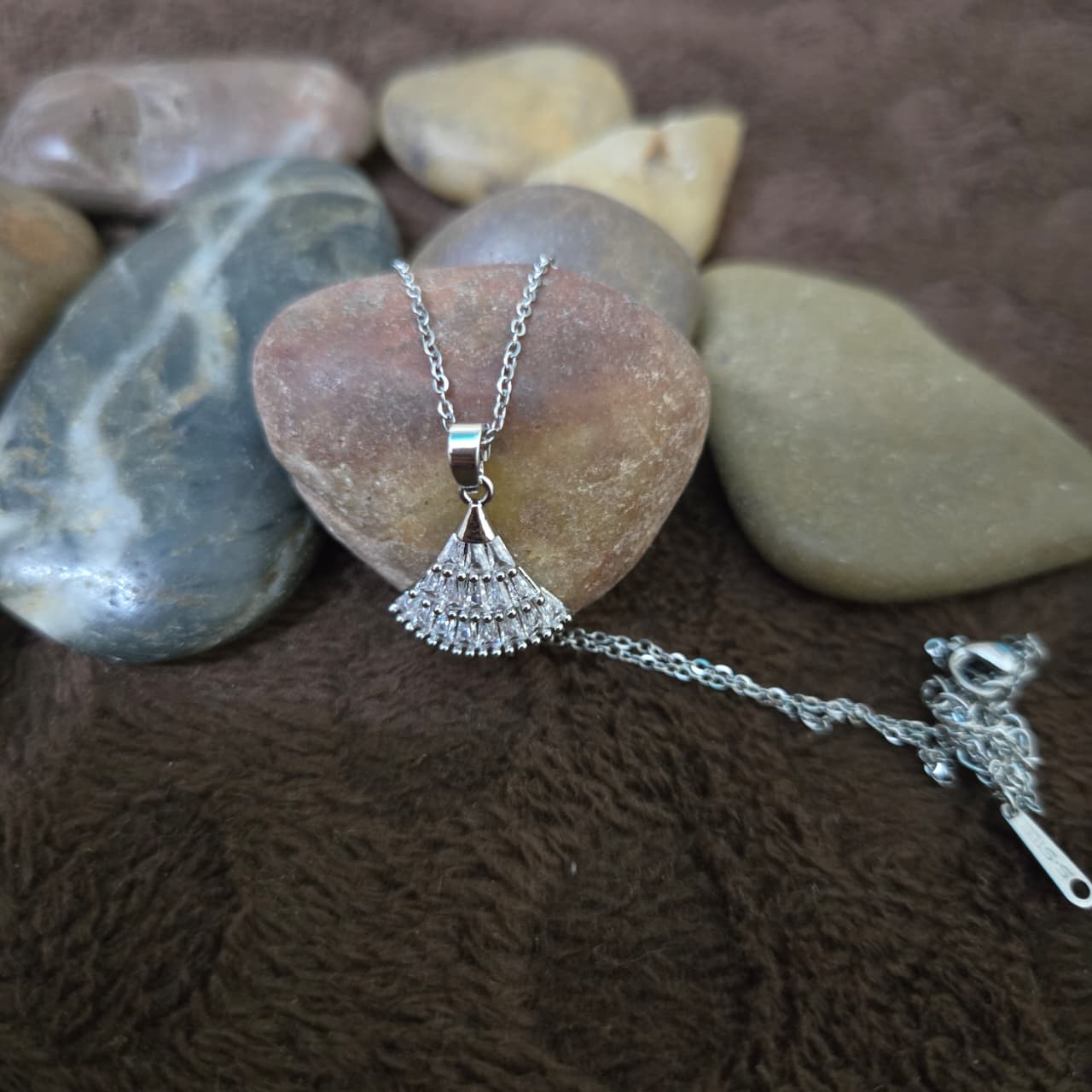 The pendant sitting on a rose stone background 