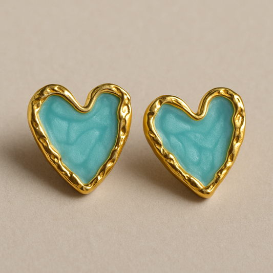 Pair of heart-shaped stud earrings with glossy black enamel centers and textured gold-toned edges, displayed on a neutral background.