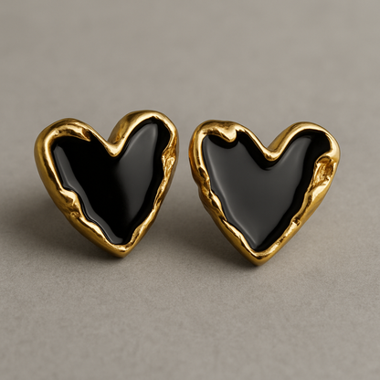 Pair of heart-shaped stud earrings with glossy black enamel centers and textured gold-toned edges, displayed on a neutral background.
