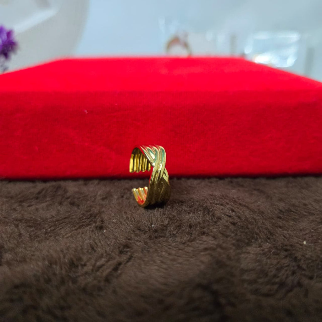 Gold ring on a brown surface with a red fabric background
