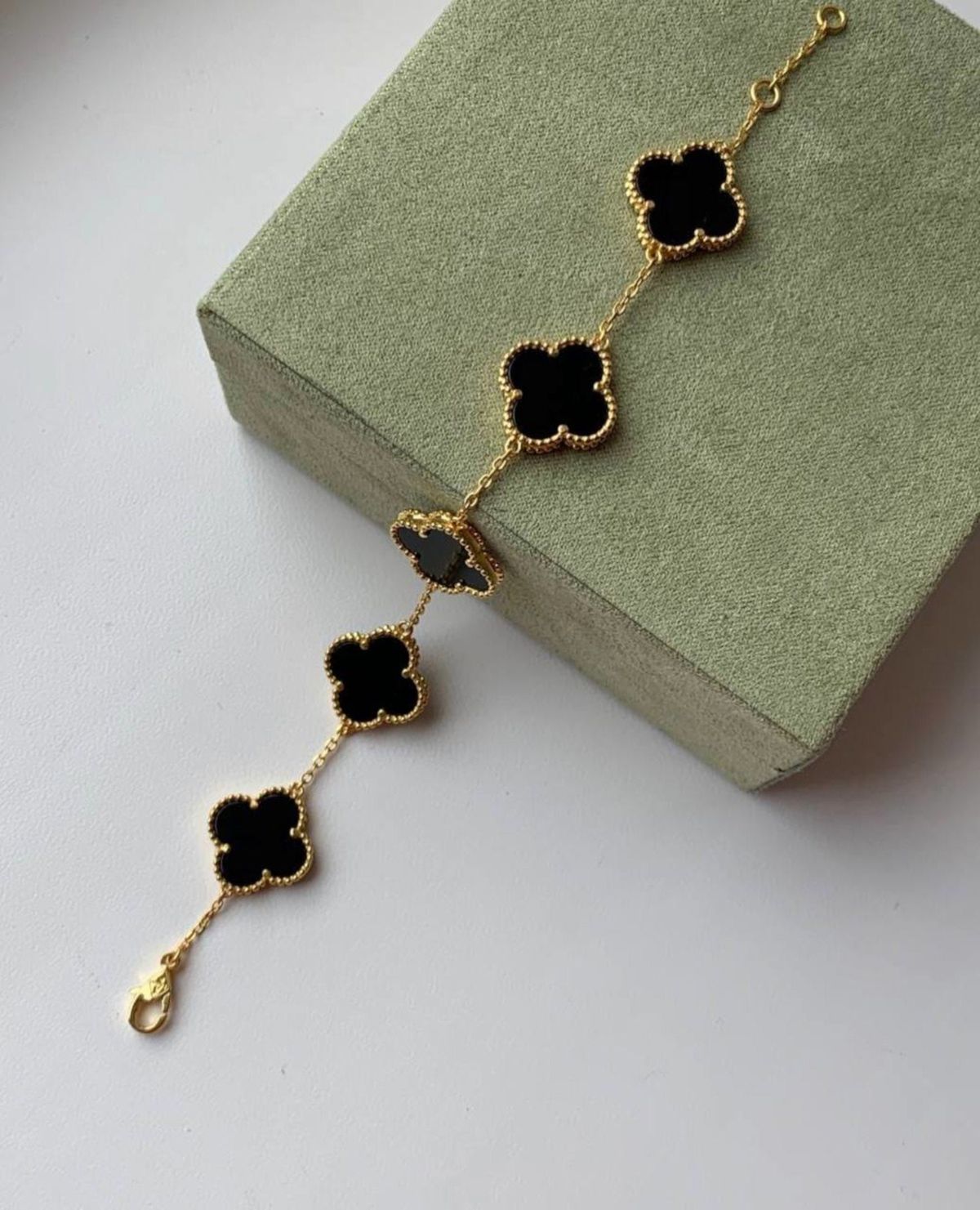 A bracelet with 5 golden clover and black inset stones.