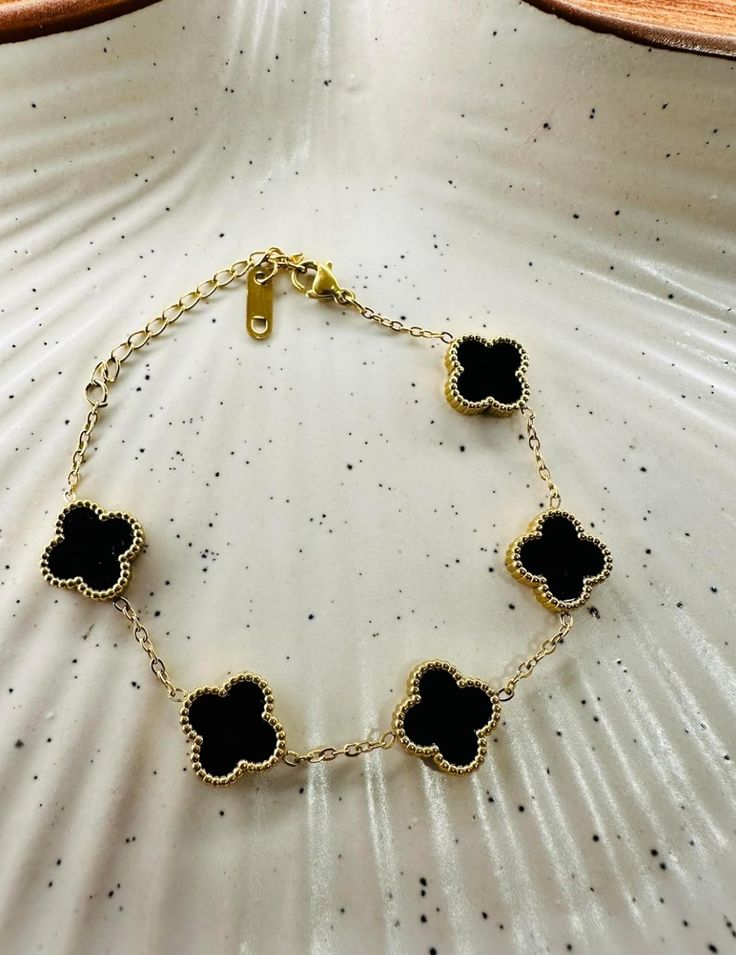 A bracelet with 5 golden clover and black inset stones.