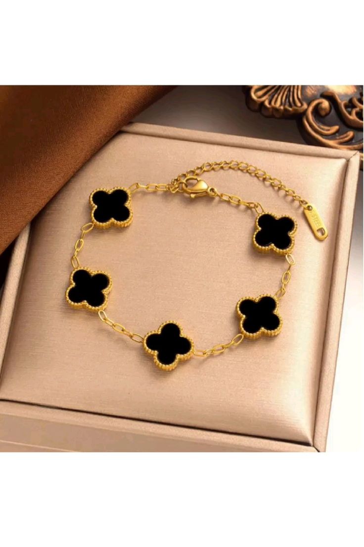 A bracelet with 5 golden clover and black inset stones.