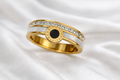Gold ring with a green gemstone on a white cloth surface