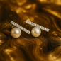 Elegant stud earrings featuring a row of sparkling crystals set in a horizontal bar above a single round pearl